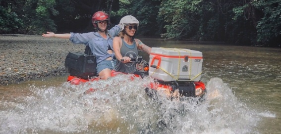 two women riding ATV through river