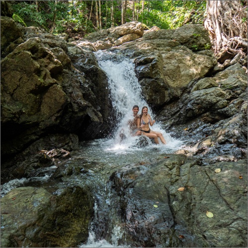 Happy couple under waterfall in Piedra Colorada river Montezuma