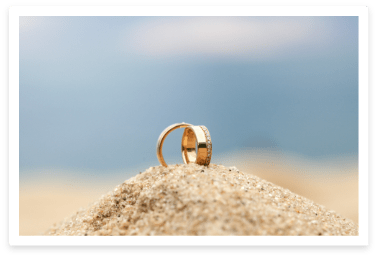 two gold wedding rings in the sand